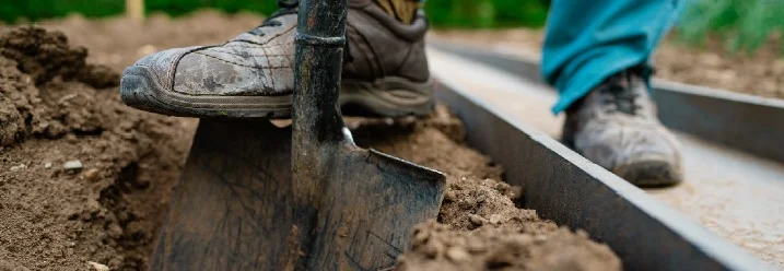 Person hebt mit einem Spaten Erde aus.